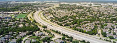 Okul bölgesi yakınlarında yüzme havuzları ve Coppell Lewisville sınırında 121 numaralı kıvrımlı karayolu olan panorama hava manzaralı banliyö evleri, arka planda karma kullanımlı depo bölgesi. ABD