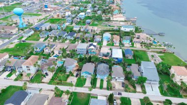 Su kulesi ve şehir merkezindeki okyanus manzaralı yerleşim yeri South Padre Adası, Laguna Koyu deniz kıyısındaki malikaneler, plaj villaları yüzme havuzu, ahşap iskele rampası, anten. ABD