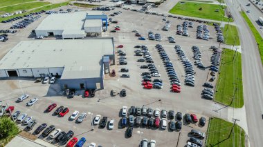 Car dealership with wide variety of auto brands display at outdoor parking lot near Interstate highway I-35 New Braunfels, outside San Antonio, Texas, new and used gas vehicles for sale, aerial. USA clipart