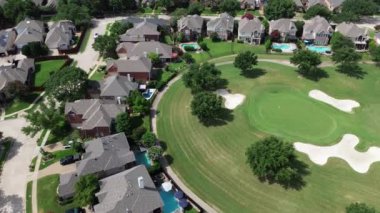 Plano, Teksas 'taki golf sahasında yüzme havuzları olan iki katlı lüks banliyö evleri kum kapanı bunalımlı çimli şehir klübü, kulüp arabaları ve golfçüler, üstgeçit.