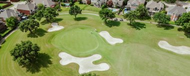 Panorama aerial view upscale two-story suburban houses with swimming pools in golf course community in Plano, Texas, grassy country club with sand trap bunkers, trees, club cars golfers playing. USA clipart