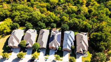 Bartonville, Denton County, Teksas, sıfır emisyon topluluğunda güneş paneli çatısı olan iki katlı evlerin yanında yemyeşil renkli yapraklar var. ABD