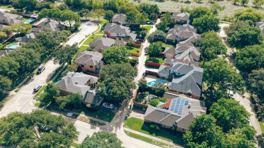 Carrollton 'da, Dallas Fort Worth Metroplex' in banliyölerinde, yemyeşil, iyi döşenmiş çim manzarasını çevreleyen lüks yerleşim alanındaki iki katlı yeni inşaat evlerinin güneş çatısı panelleri. ABD