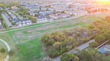 Daire kompleksi ve yerleşim bölgesi yemyeşil McKamy Patikası 'nda, Plano, Texas' ta Shady Brook Patikası 'nda, banliyö parkında gün batımı uzun bisiklet yolu, elektrik direği hattı, hava manzarası. ABD