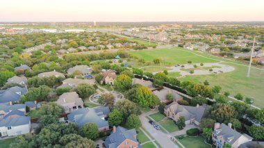 Su kulesi olan bir park kenar mahalle, yüzme havuzlu lüks malikaneler, Plano, Texas 'ta uzun yürüyüş yolları, elektrik direkleri, oyun alanı, hava sahası. ABD