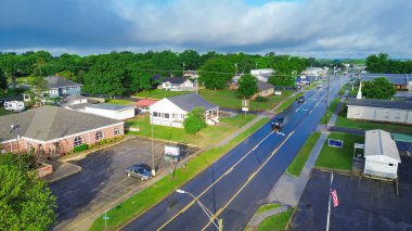 West Gentry Avenue in downtown Checotah, small town in McIntosh County, Oklahoma, mix of commercial buildings, churches, schools, residential neighborhood large houses, lush green trees, aerial. USA