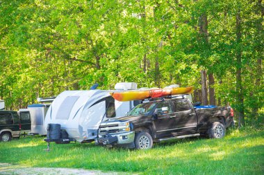 Mansfield, Missouri 'deki kır parkında kamp yapan kamyonun üstüne kayak kravatı, yemyeşil ağaçlar ve çakıllı yol, çimenli tarla, karavan karavan kamp alanı, doğa arka planı. ABD