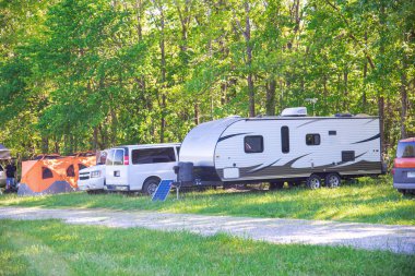 Mansfield, Missouri 'de karavan, karavan, kamyonet, çadır, yemyeşil ağaçlar, çakıl yolu, ilkbahar çayırlığı kamp alanı, doğa yaşam alanları olan taşınabilir güneş paneli. ABD
