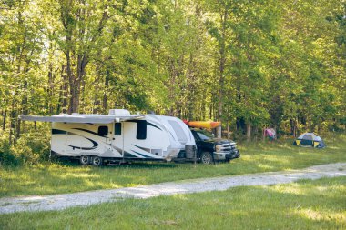 Mansfield, Missouri 'deki kır parkında kano taşıyan tente ve kamyon, yemyeşil ağaçlar, çakıl yolu, ilkbahar çayırı, karavan karavan kamp alanı, doğa yaşamı. ABD