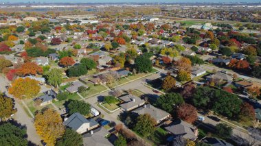 Suburban residential neighborhood detached houses with downtown Dallas in distance background, colorful fall foliage autumn leaves over Coppell, fast growing suburbs housing market, aerial view. USA clipart