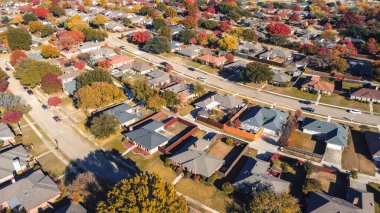 Parallel residential streets row of large single-family houses in suburban neighborhood colorful fall foliage autumn leaves in Coppell, suburbs Dallas, Texas, fast growing housing market, aerial. USA clipart