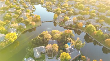 Coppell, Dallas, Teksas 'ın banliyölerindeki göl kenarındaki su çeşmesinin üzerinde renkli sonbahar yaprakları, büyük tek aile evlerinin yüzme havuzları, kiremitli çatılar, iyi döşenmiş manzara, hava. ABD