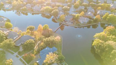 Su çeşmesi ve Coppell 'deki göl kıyısındaki yerleşim yerleri arasında küçük bir baraj Dallas, Teksas' ın varoşlarında iki katlı büyük banliyö evlerinin yüzme havuzları ve antenleri üzerinde sonbahar yaprakları var. ABD