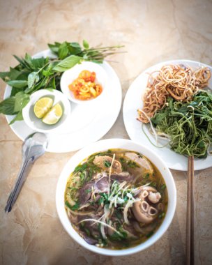 Kaşık, çubuk ve tam takım Bun Bo Hue eriştesi, pilav, sığır eti, vermicelli yuvarlak pirinç, soğan ve taze ot, limon, acı biber, Orta Vietnam 'da geleneksel baharatlı çorba. Asya