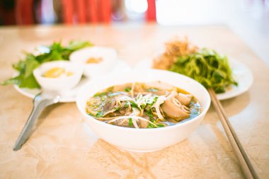 İmza: Bun Bo Hue erişteleri, pişmiş paçalarla, taze et dilimleri, pirinçli erişte, soğan ve taze ot, limon, acı biber, Orta Vietnam 'da geleneksel baharatlı çorba. Asya