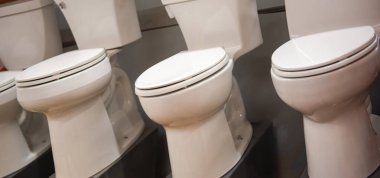 Brand new toilet bowls on display at commercial shelves in hardware home improvement store in Dallas, Texas, wide selection of elongated, round, one-piece or two-piece toilets ceramics assortment. USA clipart