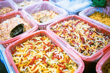 Desiccant bags in large plastic baskets with clear liner selling colorful macaroni, pasta, helical corkscrew fusilli, vegetable flat noodle at local market in Can Tho, Vietnam, organic raw vegan. Asia clipart