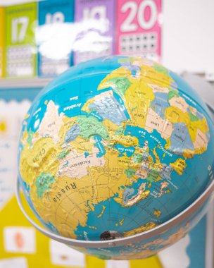 Close-up wall hanging globe raised relief metal scale bracket in kindergarten classroom in Dallas, Texas, colorful, multi-dimensional geographic world map, political boundaries, capitals, oceans. USA clipart