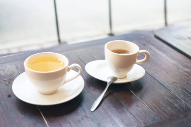 Güney Vietnam, Can Tho 'daki yerel kahve dükkanının ahşap masasında çay fincanı ve çay fincanı ile sarı papatya çayı bardağı, sıcak porselen bardaklar. Asya