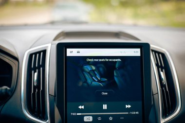 Arka koltukta, park halindeki modern SUV aracının 12 inçlik LCD dokunmatik ekranını kontrol edin. Sistem, sürücüleri, araçtan çıkmadan önce arka koltukları kontrol etmeleri, çocukları veya hayvanları başıboş bırakmamaları için alarma geçirsin. ABD