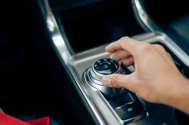 Adam, Amerika 'daki lüks SUV arabasının orta konsolunda el dönüşlü vites kolu kullanarak kısa giyer. Çevir vites seçici P, R, N, D ve S Sport modunda otomatik vites kullanır. ABD