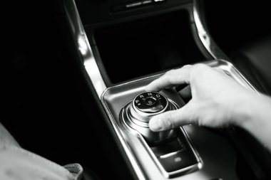 Adam, Amerika 'daki lüks SUV arabasının orta konsolunda el dönüşlü vites kolu kullanarak kısa giyer. Çevir vites seçici P, R, N, D ve S Sport modunda otomatik vites kullanır. ABD