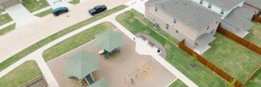 Panorama hava manzaralı oyun alanı gölgeli yapılar, salıncakta sallanan çocuklar, Princeton, Collin County, Teksas 'ta yeni bir inşaat alanında kaydırak, iki katlı lüks banliyö evleri. ABD