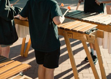 Marimba tokmağı oynayan ilkokul öğrencileri Coppell, Texas 'taki halk parkında ahşap döşeme tahtası, PVC borular ve orkestralarla inşa edilmiş bir enstrümanla müzik performansı sergilediler. ABD