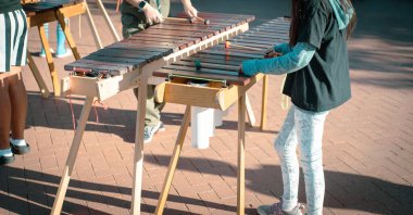 Panorama manzaralı ilkokul öğrencileri Coppell, Texas 'taki halk parkında marimbas tokmağı oynuyorlar. Tahta döşeme tahtalarında, PVC borularda ve orkestralarda yapılan enstrümanlarda açık hava müzik performansı. ABD