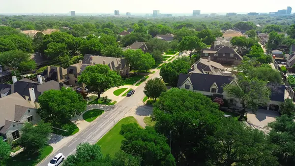 Sessiz ağaç, zengin Preston Hollow mahallesindeki milyonlarca dolarlık malikaneler boyunca uzanan, arka planda yüksek katlı apartman daireleri, yemyeşil. ABD