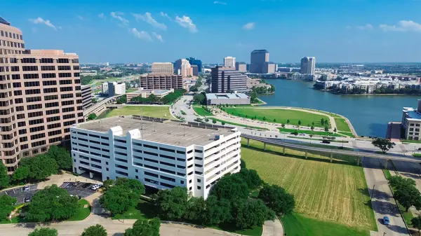 Las Colinas, Irving, Lake Carolyn 'in göl kenarındaki büyük şehir merkezindeki çok katlı otopark, göl kenarındaki yerleşim birimleri, aydınlık raylar. ABD