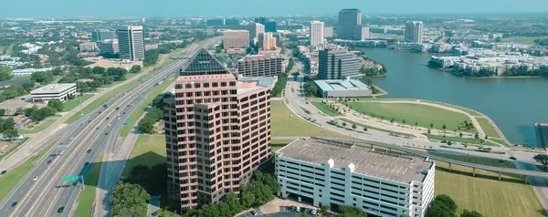Panorama hava manzaralı Texas State Highway SH 114, John Carpenter Freeway, Las Colinas şehir merkezindeki hafif rayları yükseltti büyük şehir merkezi, ofis binaları, göl kenarındaki apartmanlar, evler. ABD