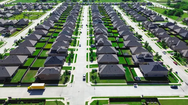 Park etmiş arabaların olduğu yerleşim yerlerinin kesiştiği yer modern tek aile evlerinin olduğu sıra sıra genç ağaçlar ana yerleşim yeri Myrick Lane, Princeton, Teksas 'taki çimlerin peyzajını yapıyor. ABD