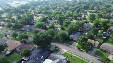 Cockrell Hill Mahallesi, Güney Dallas, TX 'teki orta sınıf tek aile evlerinin kiremitli çatıları üzerinde güneş panelleri yerleşim alanı olarak kurulmuş yemyeşil, ağaçlarla kaplı caddeler, tepedeki elektrik hatları.