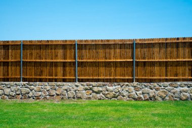 Duvar temeli ve ahşap çit, doğal dış ahşap leke, Princeton, Teksas 'taki yeni inşaat evinin yuvarlak çit kaplama destesi, arka bahçe mahremiyeti. ABD