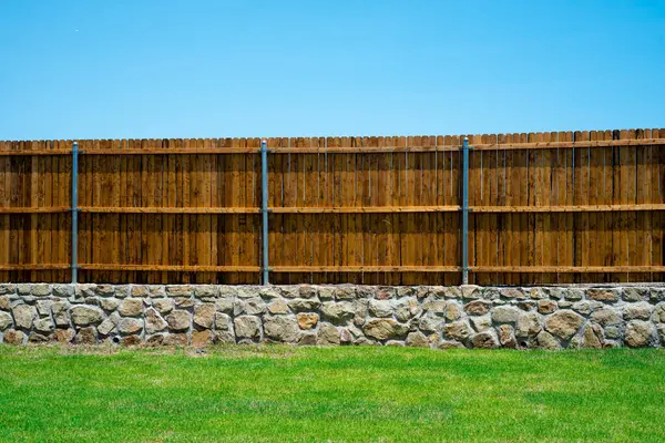 Duvar temeli ve ahşap çit, doğal dış ahşap leke, Princeton, Teksas 'taki yeni inşaat evinin yuvarlak çit kaplama destesi, arka bahçe mahremiyeti. ABD