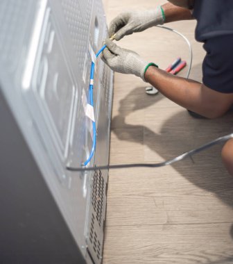 Bakır su hattını birbirine bağlayan eldiven takan teknisyen vinil temiz mutfaktaki yepyeni buzdolaplarının arkasına yeni buzdolabı için su hattı kuruyor. Cihaz kurulumu sırasında ellerinizi yakın tutun. ABD