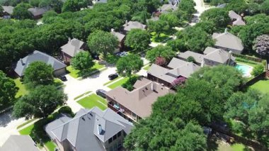 Ağaç kaplı konut caddesi, yemyeşil banliyö mahallesi, bakımlı yeşil çimenleri olan modern iki katlı evler güneşli bir yaz gününde garaj yolu parkı, Çiçek Tepesi, Teksas, üstgeçit.