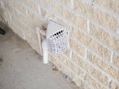 Tuğla duvarda yoğun biçimde tıkanmış pamuk menfezi kapağı, hava akışını engelleme, yangın tehlikesi oluşturma. Görülebilir bitişik PVC borular, biriken borular kötü havalandırma, bakım gerektiren temizlik. ABD