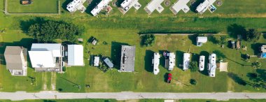 Port Bolivar 'daki yükseltilmiş sahil evinin yanındaki çimenli bahçeye park edilmiş panorama hava manzaralı karavan karavanları. Sahne, Galveston Körfezi bölgesindeki esnek kıyı yaşam tarzını yakalıyor. ABD