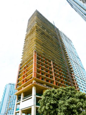 Beton zemin, kırmızı tuğla duvarlar, iskelet kulesinin hakimiyetindeki inşaat asansörü beyaz arka planda izole edilmiş, Danang 'da ölçek, yapı ve dikey büyümeyi vurguluyor. Vietnam