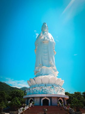 Linh Ung Tapınağı 'ndaki büyük beyaz Buda heykeli, Da Nang, Lotus kaidesinin üzerinde dimdik duruyor, dalgalı kaftanları, kavisli çatıları, ejderha oymaları, güneşli mavi gökyüzünün altındaki sütunları. Vietnam