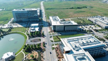 Lakeside amphitheater circular pond, rooftop HVAC office buildings, multilevel parking garage, restaurant patios, North Lake trails, large vacant land future development in Cypress Water, Dallas. USA