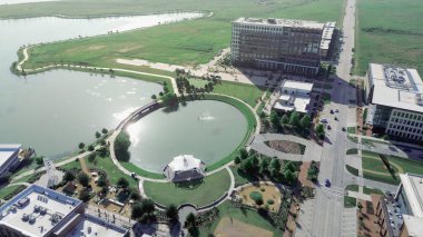 Circular pond with white pavilion, surrounded by North Lake trails, restaurant patios, office buildings along Cypress Waters Boulevard, showcasing entertainment and waterfront lifestyle in Dallas. USA