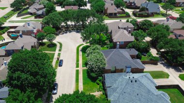 Quiet cul-de-sac in North Coppell, Texas, featuring two-story homes with sloped shingle roofs, fenced backyards, mature trees, and curved streets in a master-planned HOA community suburbs Dallas. USA