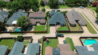 Upscale suburban homes in Coppell, Texas with solar panel rooftops, fenced yards, backyard pools, rear alley garage, tree-lined streets in sustainable, family-friendly neighborhood suburbs Dallas. USA