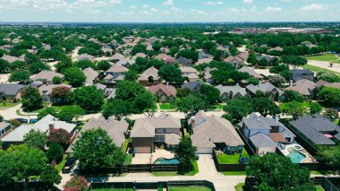 Coppell, Teksas 'ta iki katlı banliyö evleri olan yerleşim yerleri olgun ağaçlar, çitli bahçeler, yüzme havuzları, Coppell Lisesi kampüsü ve arka planda Plano siluetleri. ABD