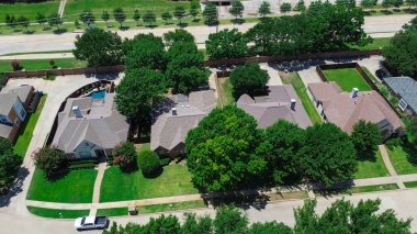 Landscaped tree row along Parkway Boulevard in Coppell, Texas, two-story suburban homes border by brick fence, drainage sewer system concrete channels, municipal investment stormwater management. USA