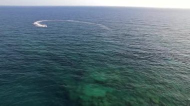 Güneşli bir günde tropikal mavi suda jet ski süren bir adam. Havadan. Yüksek kalite 4k görüntü