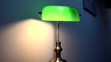 Kahverengi bir masanın üzerinde şık yeşil bir okuma lambası duruyor. Lüks apartman dekoru. Yüksek kalite 4k görüntü